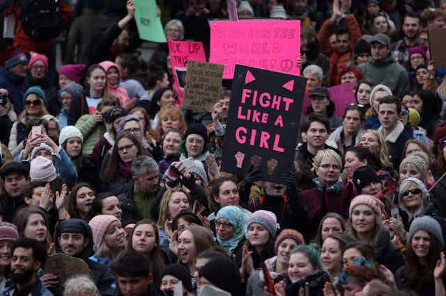 A group of mostly white women hold signs. One reads 'fight like a girl.'