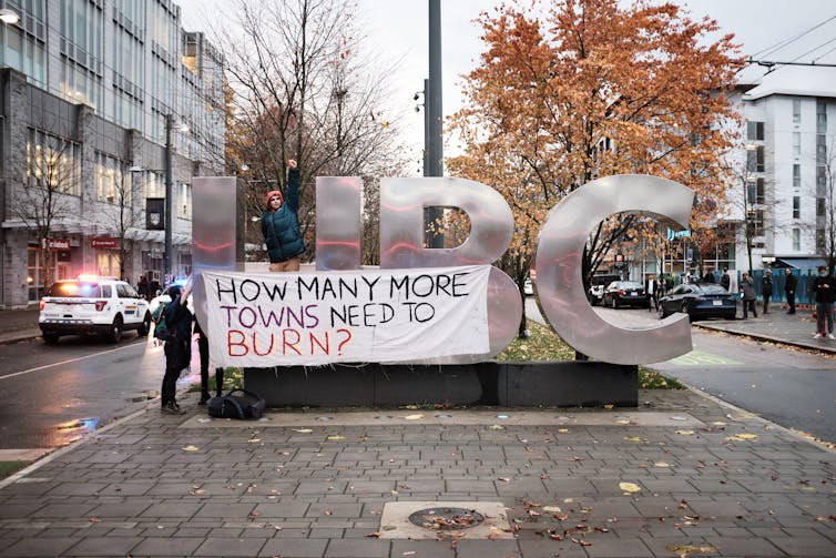 A person is seen with a protest banner on a university logo.