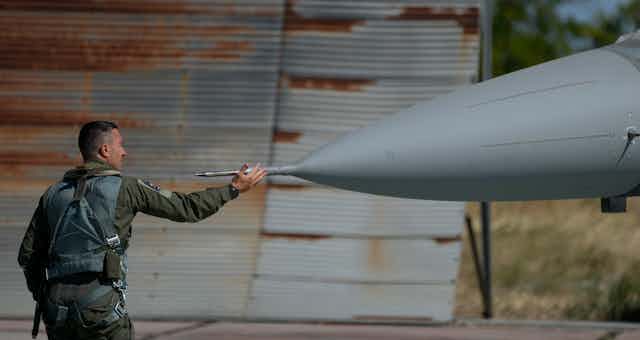 A soldier touches the nose of his fighter jet.