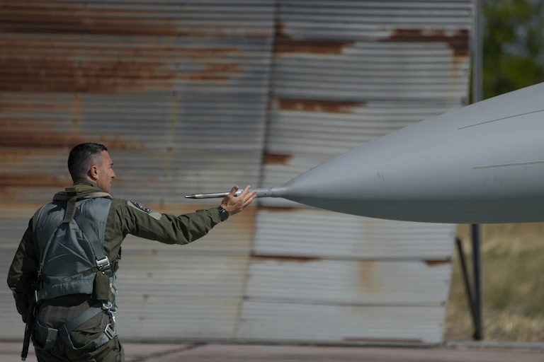 A soldier touches the nose of his fighter jet.