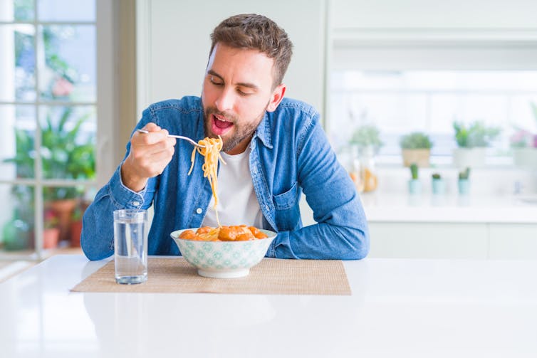 A man eats a large bowl of pasta.