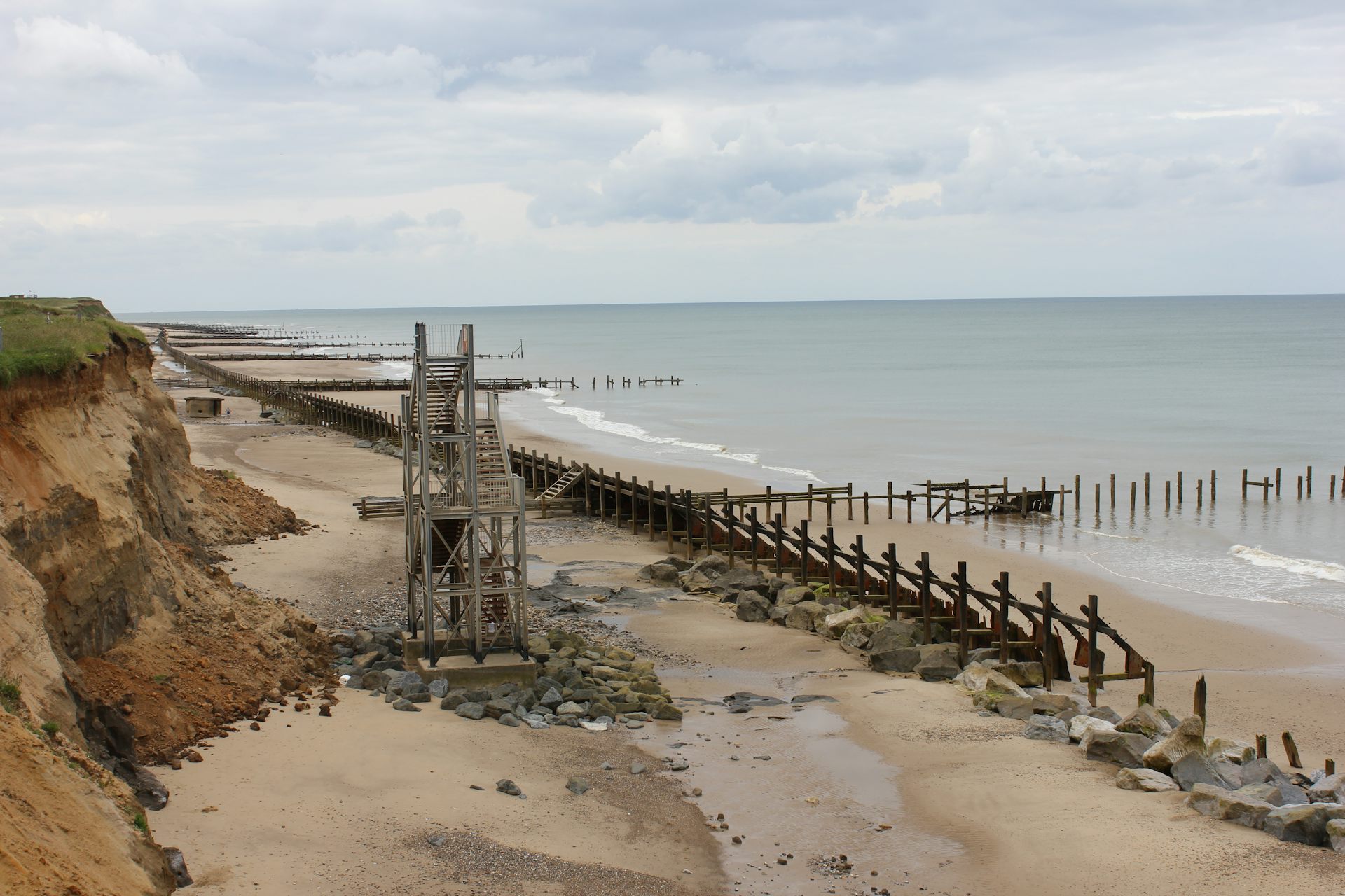 A beach lined with wooden groynes and other structures.