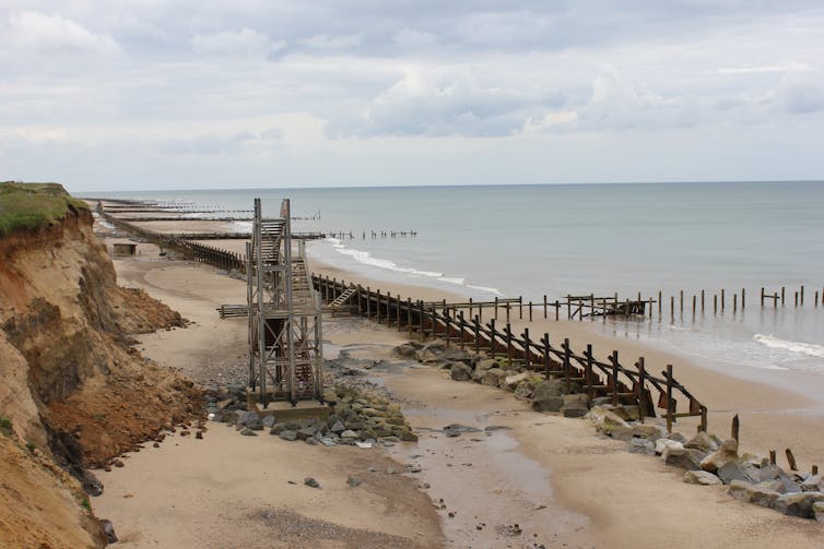 A beach lined with wooden groynes and other structures.