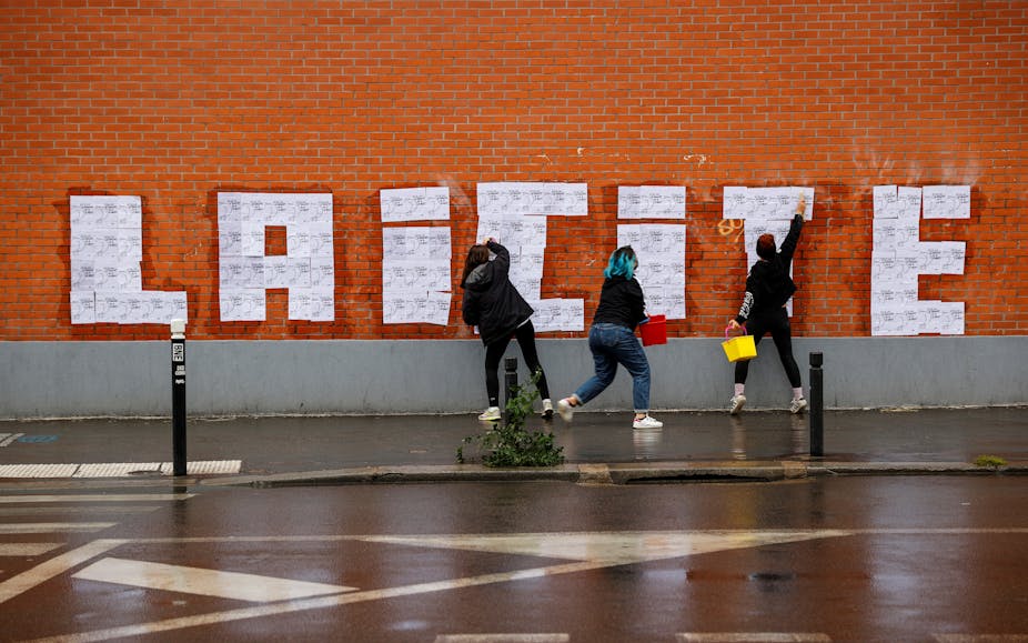 Trois militantes féministes font un collage sur un mur à Montreuil le 20 octobre 2020 lors d'un événement hommage à la rédaction de Charlie Hebdo.