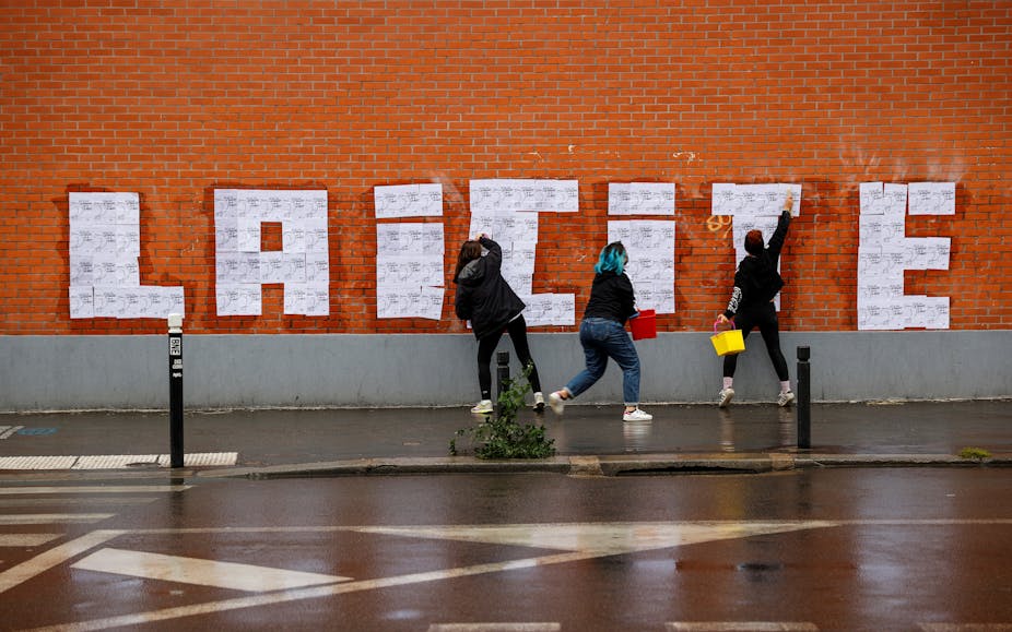 Trois militantes féministes font un collage sur un mur à Montreuil le 20 octobre 2020 lors d'un événement hommage à la rédaction de Charlie Hebdo. 