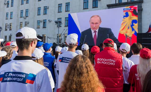  Local people watch a live broadcast of Russian President Vladimir Putin's speech after a ceremony to sign treaties on new territories' accession to Russia in downtown Luhansk