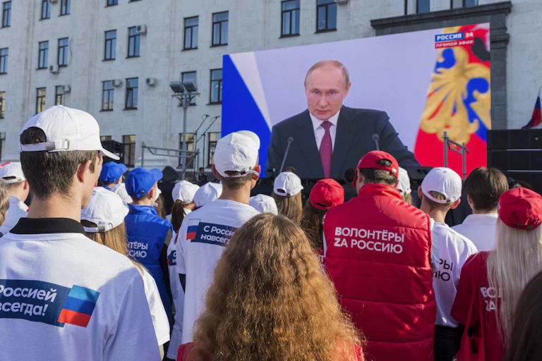 Local people watch a live broadcast of Russian President Vladimir Putin's speech after a ceremony to sign treaties on new territories' accession to Russia in downtown Luhansk