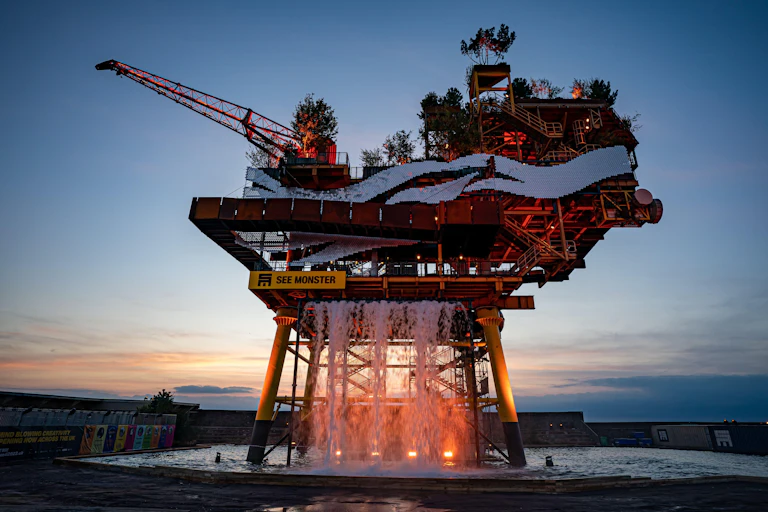 A huge oil rig with tress and water fall on it.
