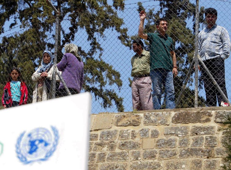 القبارصة الأتراك يقفون خلف سياج يفصل شمال قبرص عن منطقة نيقوسيا الخاضعة لسيطرة القبارصة اليونانيين