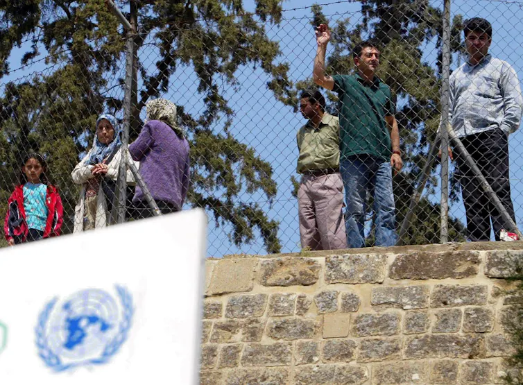Turkish Cypriots stand behind a fence dividing northern Cyprus from the Greek Cypriot controlled area of Nicosia, Cyprus