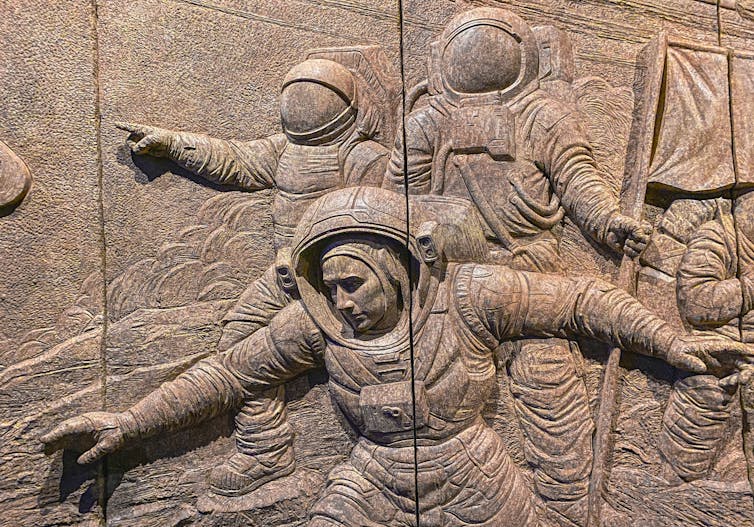 a mural in relief showing astronauts approaching an unseen something