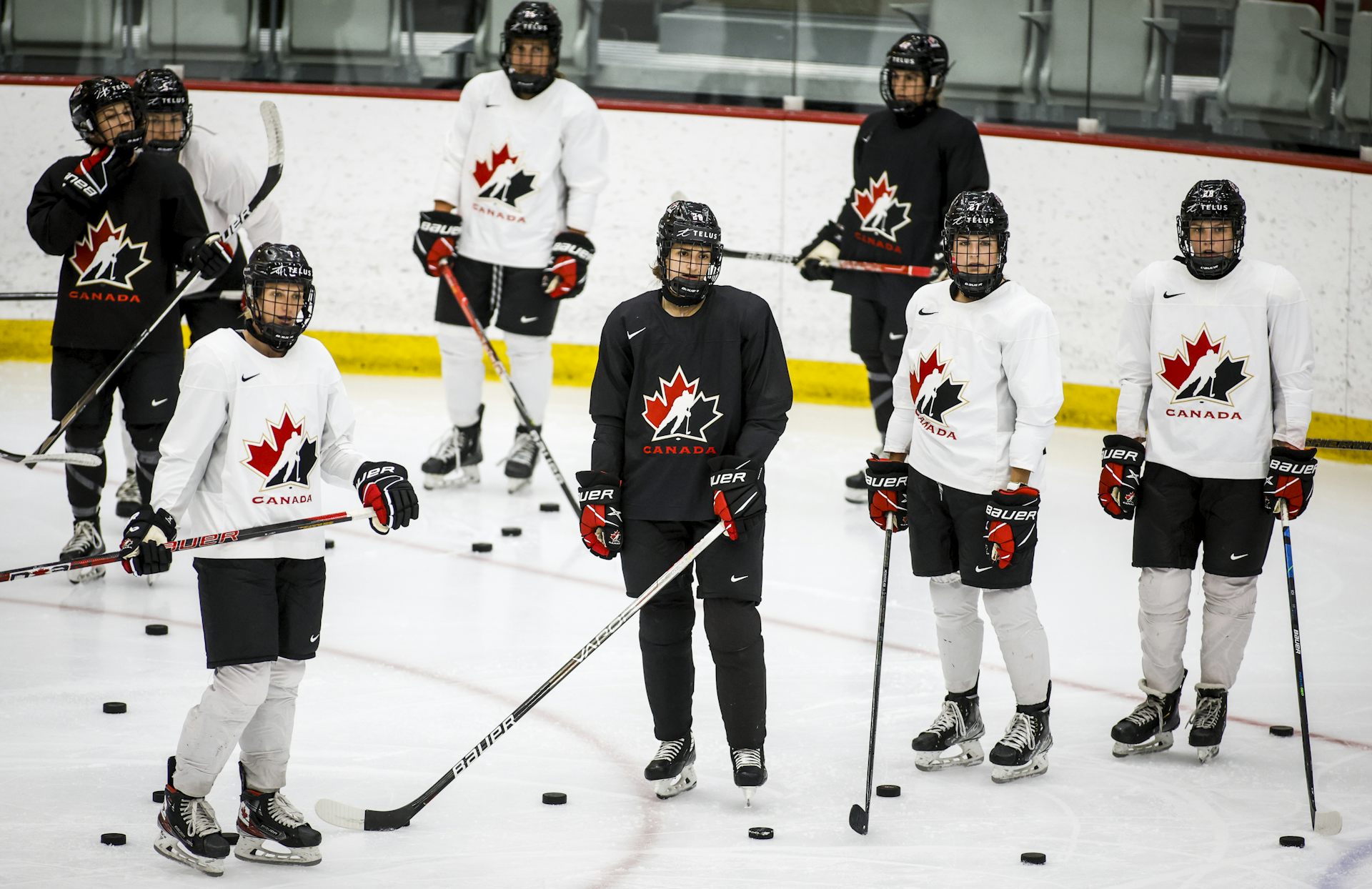 women in hockey gear stand on the rink.