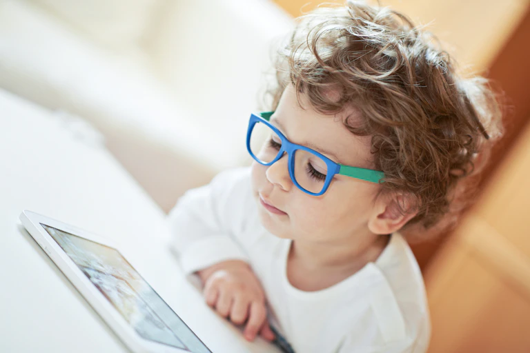 jeune garçon avec des lunettes regarde une tablette électronique