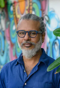 A young handsome Sri Lankan man in blue glasses and shirt.