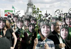 People carry placards of the face of a dark-haired woman.
