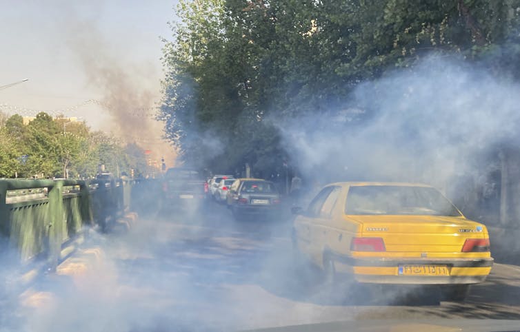 A yellow car is seen amid a cloud of tear gas.