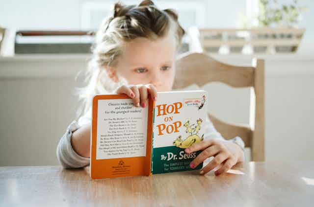 Young girl reading the book 'Hop on Pop'. 