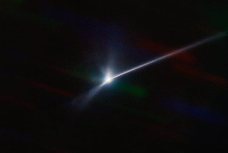 A glowing point of light on a dark background with a streak extending to one side