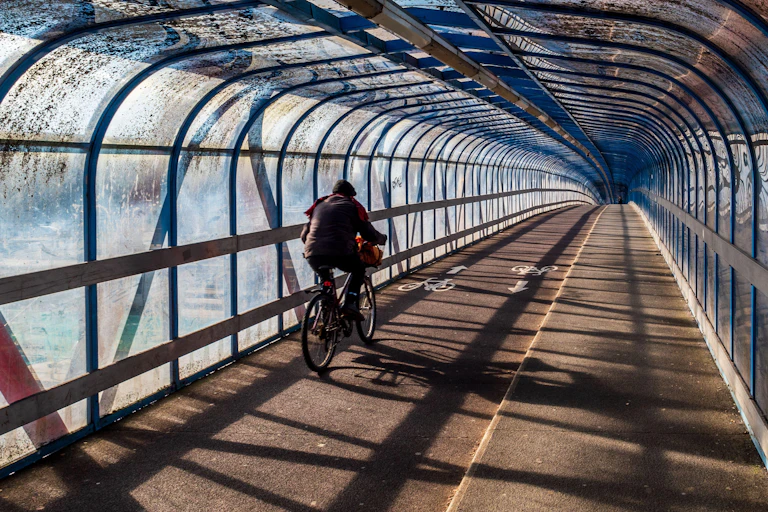 A cyclist pedals down an empty sheltered bike lane.