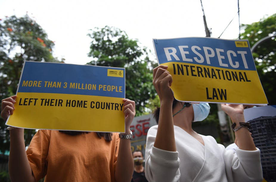 Des personnes manifestent avec des pancartes d'Amnesty International en faveur de l'Ukraine