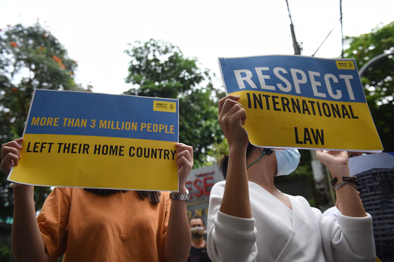 Des personnes manifestent avec des pancartes d'Amnesty International en faveur de l'Ukraine