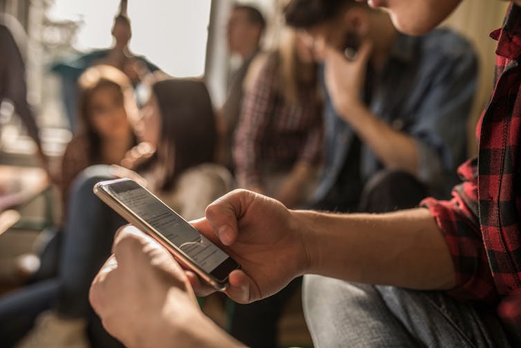 A person holds a cellphone in a crowded room.