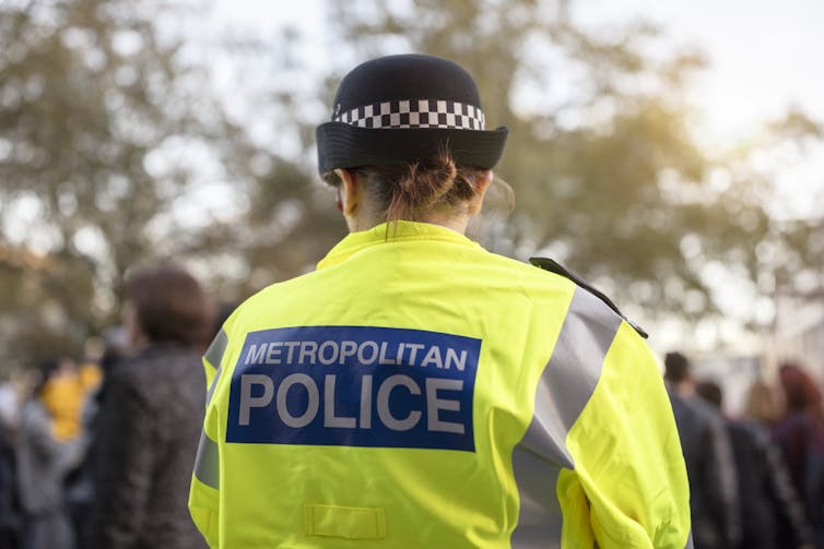 View from behind of a female Met police officer in a high vis jacket