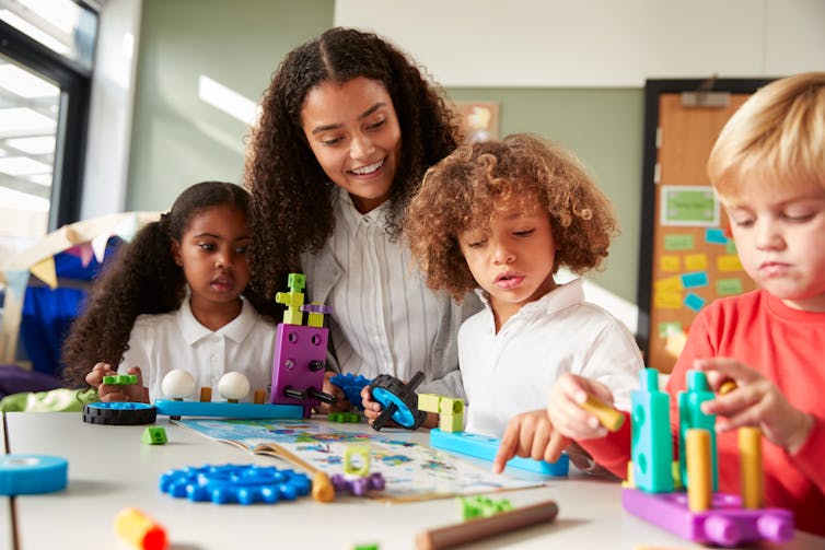 An educator seen at a desk with students.