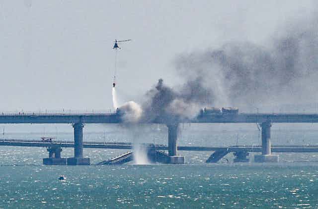  A firefighter helicopter pours water on fire on a collapsed part of the Kerch Strait bridge in Crimea, 08 October 2022