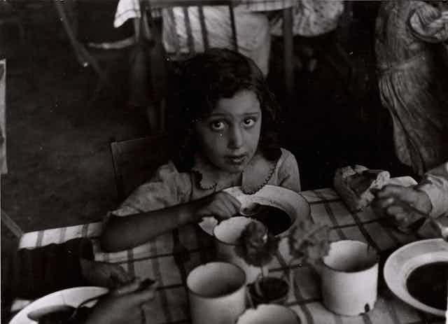 Una niña mira a cámara mientras come con una cuchara.