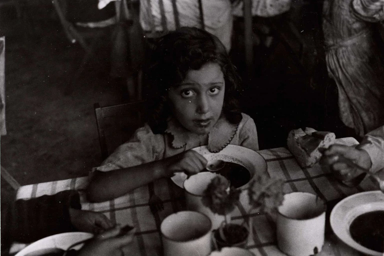 Una niña mira a cámara mientras come con una cuchara.