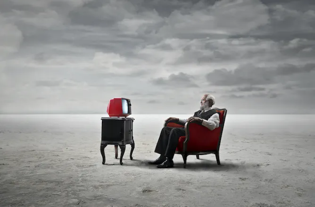 Dreamscape: lelaki tua menonton televisi di dataran berpasir.