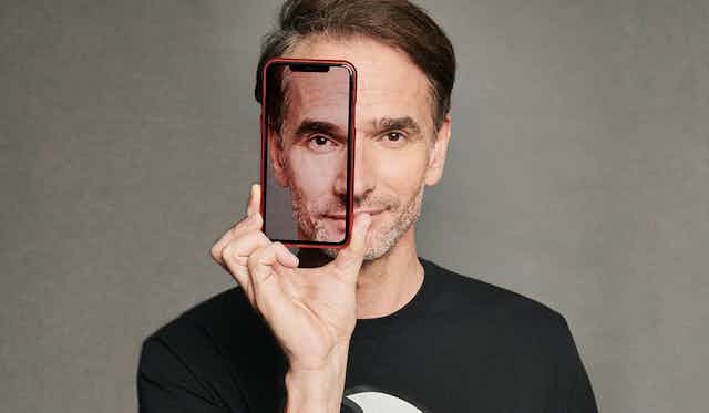 A man in a black t-shirt looking at the camera through a transparent phone case