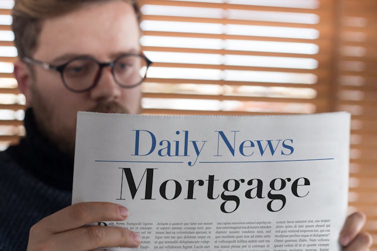 Man reading newspaper headlines about mortgages.