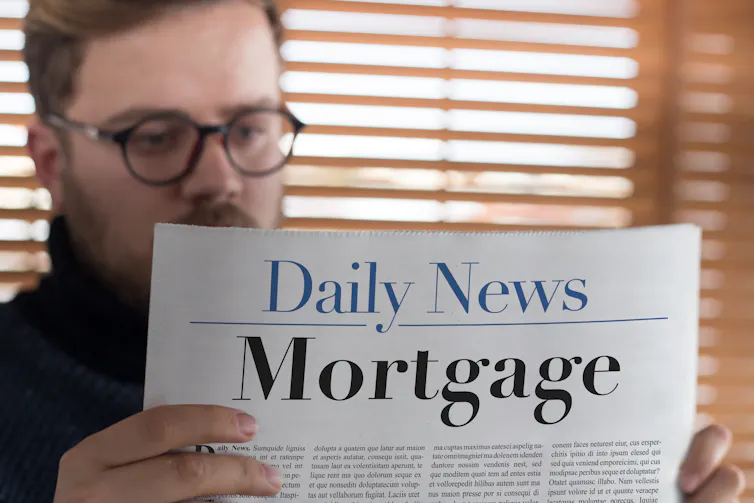 Man reading newspaper headlines about mortgages.