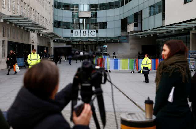 Members of the media wait as the BBC logo is seen outside Broadcasting House, as the corporation announced it will cut around 450 jobs from its news division, in London, Britain January 29, 2020.