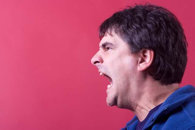 Side profile of man screaming.