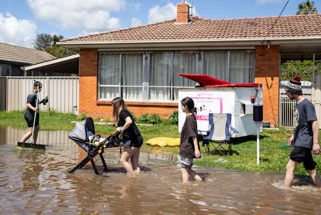 You people walk through flooded road in front of home