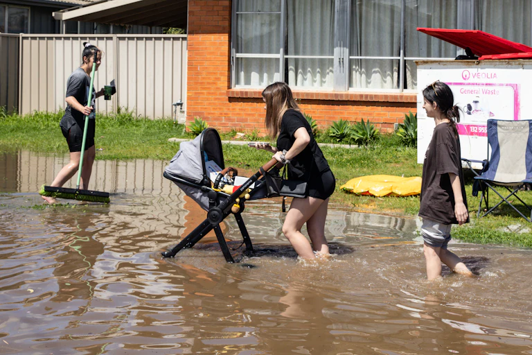 You people walk through flooded road in front of home