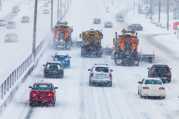 cars follow behind three snowplows on a highway