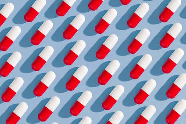 Illustration of red and white pills lined up against a blue background