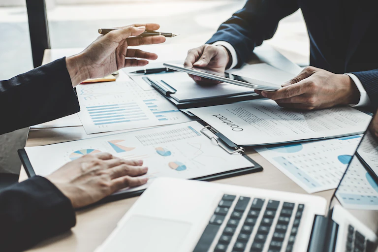 hands indicating a conversation about financial documents spread on a table.
