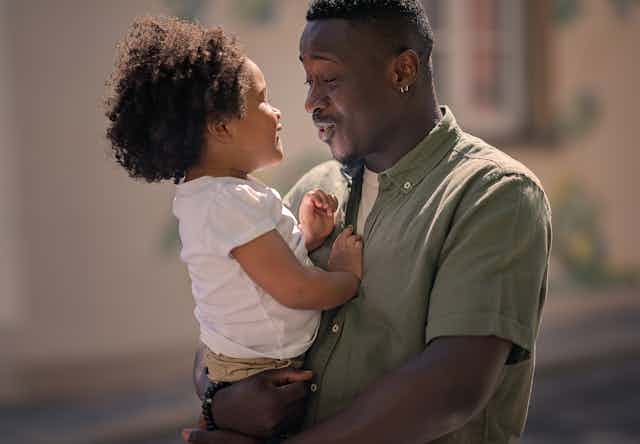 Father holding small daughter and having conversation together