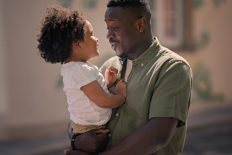 Father holding small daughter and having conversation together