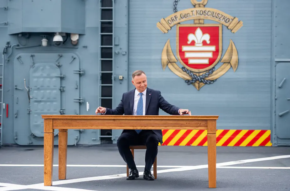 Andrzej Duda sitting at a table on a warship