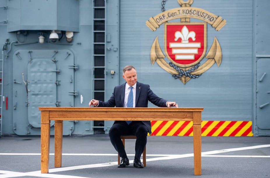 Andrzej Duda sitting at a table on a warship