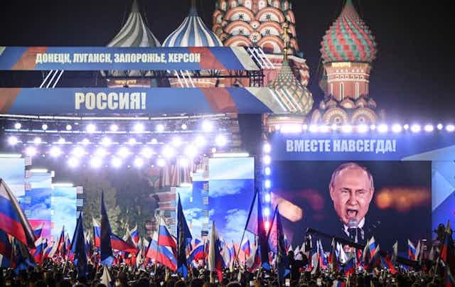 Nuée de drapeaux russes sur la place Rouge à Moscou, de nuit. Banderoles « Donetsk, Lougansk, Zaporijia : Russie » et « Ensemble pour toujours ».
