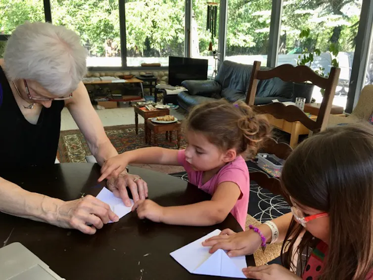 A child seen working with paper explaining something to an adult.