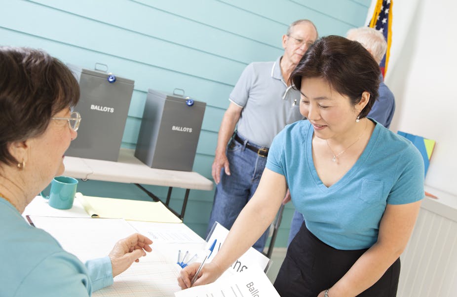 An Asian American woman registering to vote at the polling station.