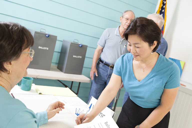 An Asian American woman registering to vote at the polling station.